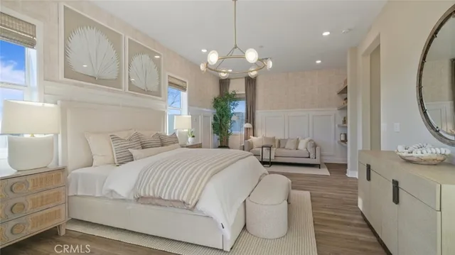 a spacious bedroom with a bed a chandelier and a mirror on the dresser