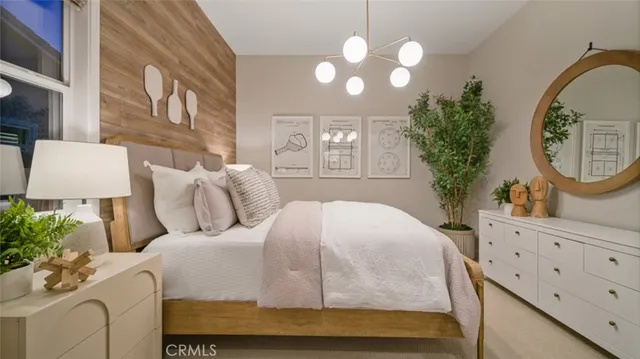 a bedroom with a bed a mirror on dresser and a chandelier