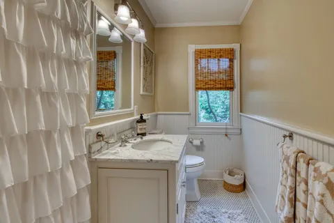 a bathroom with a granite countertop sink a toilet and a window