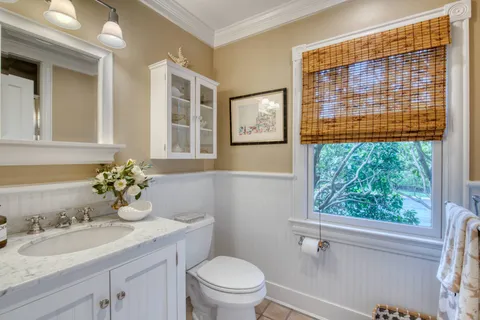 a bathroom with a granite countertop sink vanity mirror and toilet