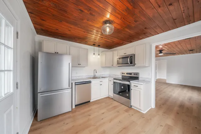 a kitchen with stainless steel appliances granite countertop a refrigerator a stove a sink dishwasher and a refrigerator with wooden floor