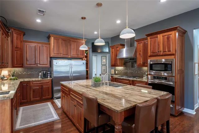 a kitchen with stainless steel appliances granite countertop wooden cabinets a stove and a sink