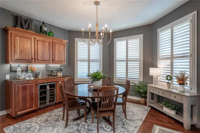 a dining room with wooden floor a chandelier a wooden table and chairs