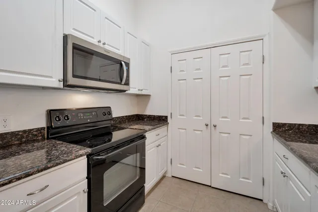 a kitchen with stainless steel appliances granite countertop a sink a microwave a refrigerator and white cabinets