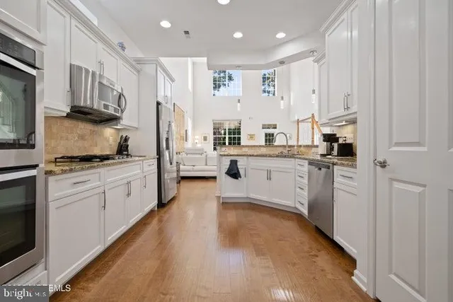 a kitchen with stainless steel appliances granite countertop a refrigerator sink and white cabinets