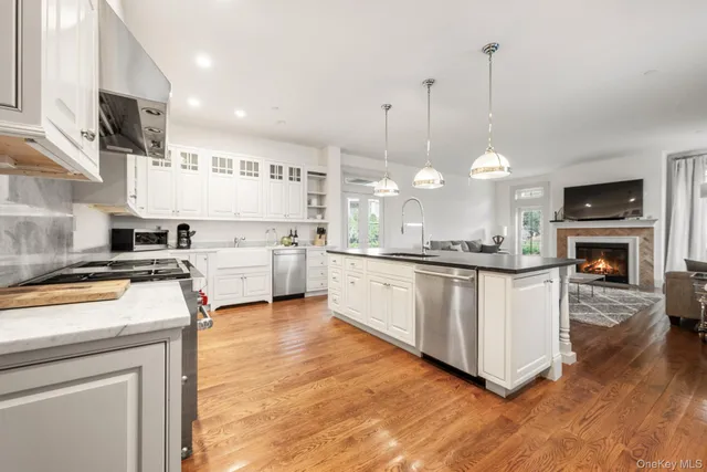 a kitchen with stainless steel appliances granite countertop a stove a sink and a wooden floor