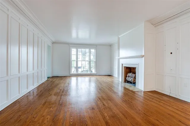 an empty room with wooden floor fireplace and windows