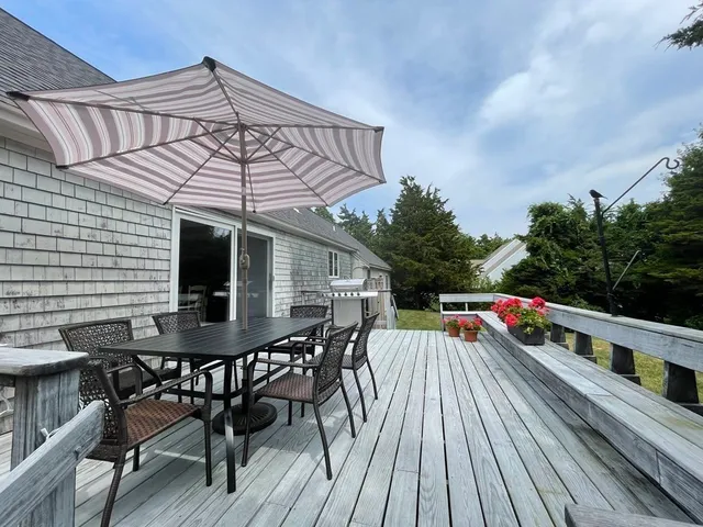a view of a roof deck with table and chairs a barbeque with wooden floor and fence