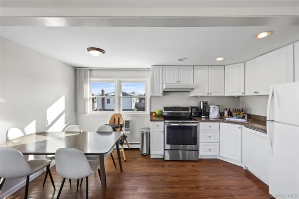 a kitchen with stainless steel appliances a stove a sink a refrigerator and white cabinets with wooden floor