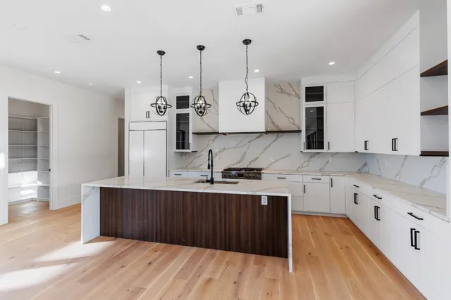 a view of an empty room with wooden floor and a chandelier