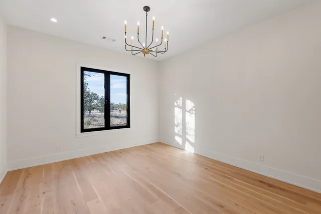 a view of an empty room with window and wooden floor