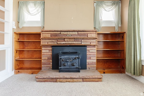 365 West 200 North Logan, UT 84321 - Photo 5 of 45 Central stone fireplace with a cast-iron wood-burning stove, flanked by built-in wood shelving units