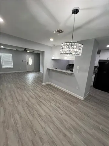 a view of an empty room with window and wooden floor