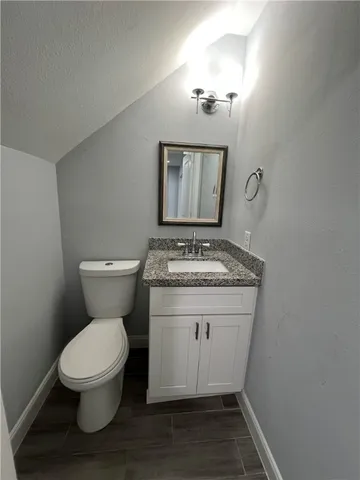 a bathroom with a granite countertop toilet and a sink