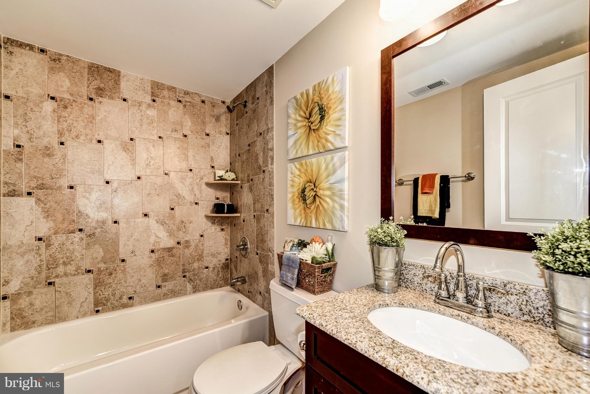506 Midland Road Silver Spring, MD 20904 - Photo 18 of 28 a bathroom with a granite countertop sink a toilet a mirror a bathtub and shower