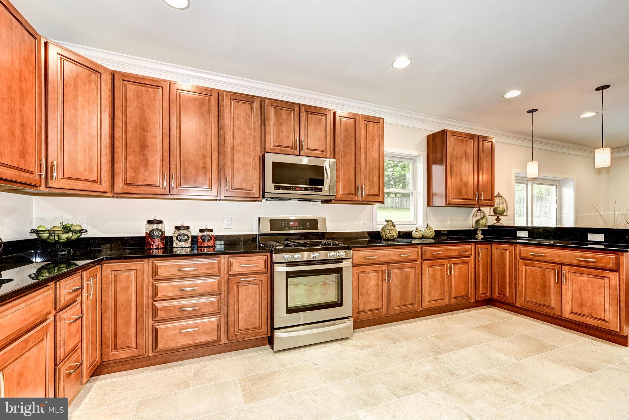 506 Midland Road Silver Spring, MD 20904 - Photo 23 of 28 a large kitchen with stainless steel appliances granite countertop a stove top oven a sink dishwasher and wooden cabinets with large window