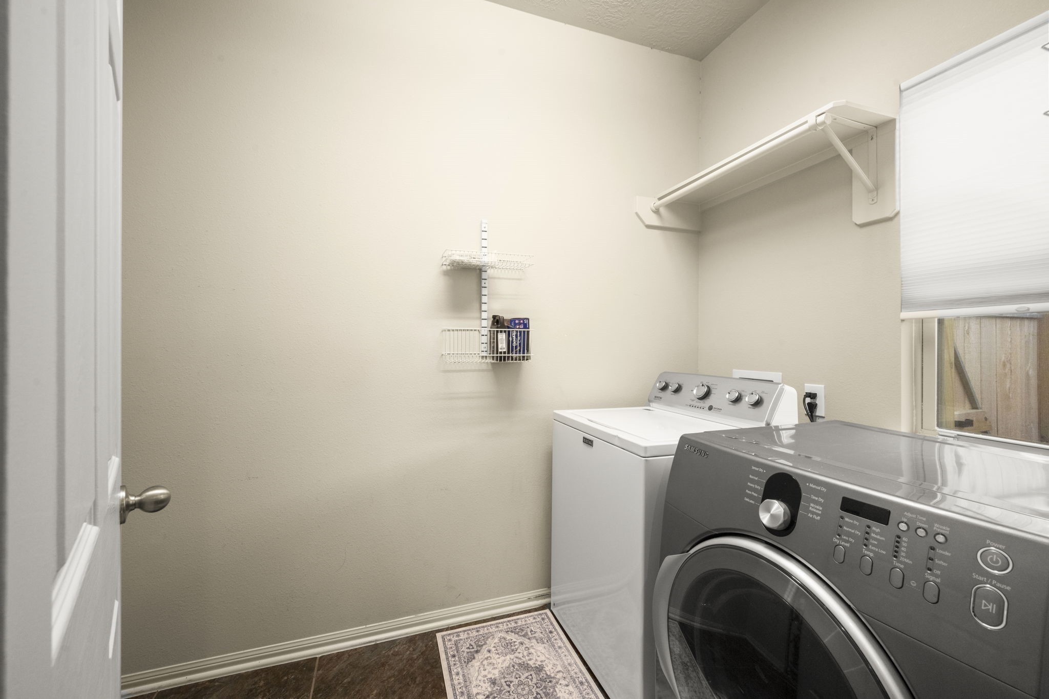 27526 Gatlin Lane Spring, TX 77386 - Photo 13 of 31 Thoughtfully laid out, this laundry room offers a washer and dryer, efficient wall storage, and natural lighting from a window—everything you need in a bright, organized space.