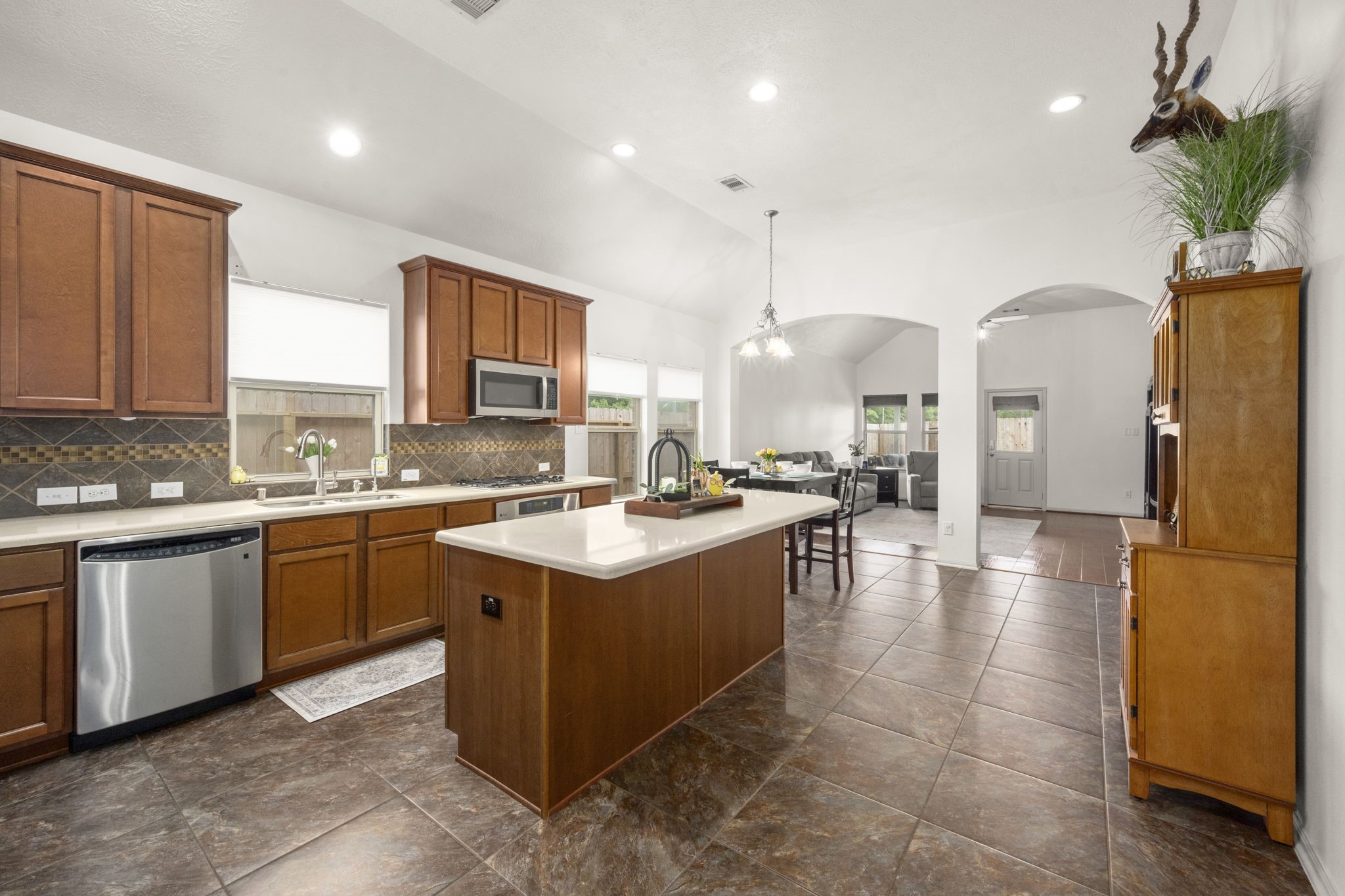 27526 Gatlin Lane Spring, TX 77386 - Photo 4 of 31 Spacious, modern kitchen with a large island and sleek stainless steel appliances. Rich wooden cabinets complement the tiled floor, and the open-concept design flows into a cozy living area with ample natural light.