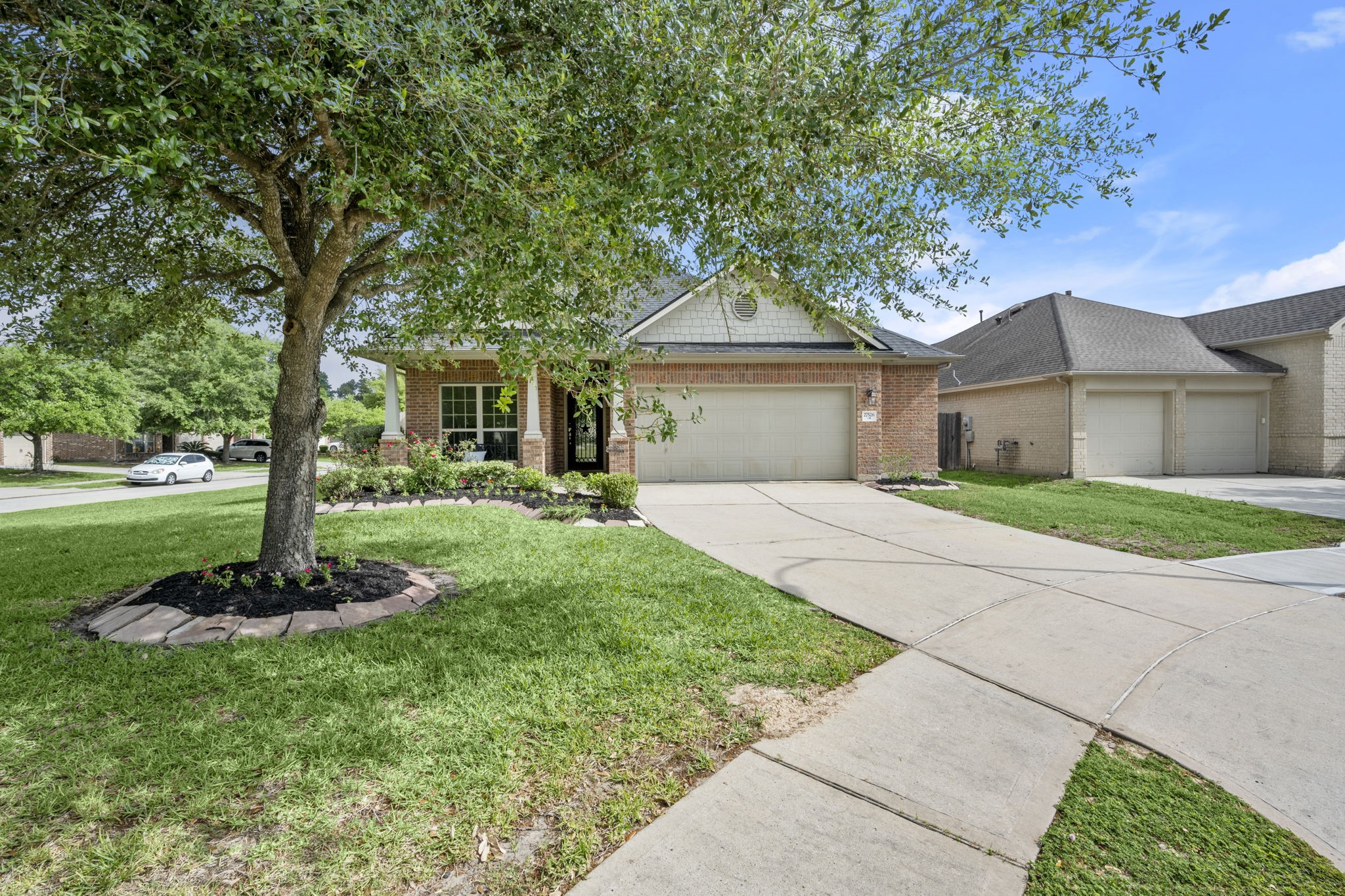 27526 Gatlin Lane Spring, TX 77386 - Photo 5 of 31 Charming single-story brick home with a two-car garage, a well-maintained front yard, and a large tree offering shade. The driveway curves gracefully, leading to a welcoming front porch.