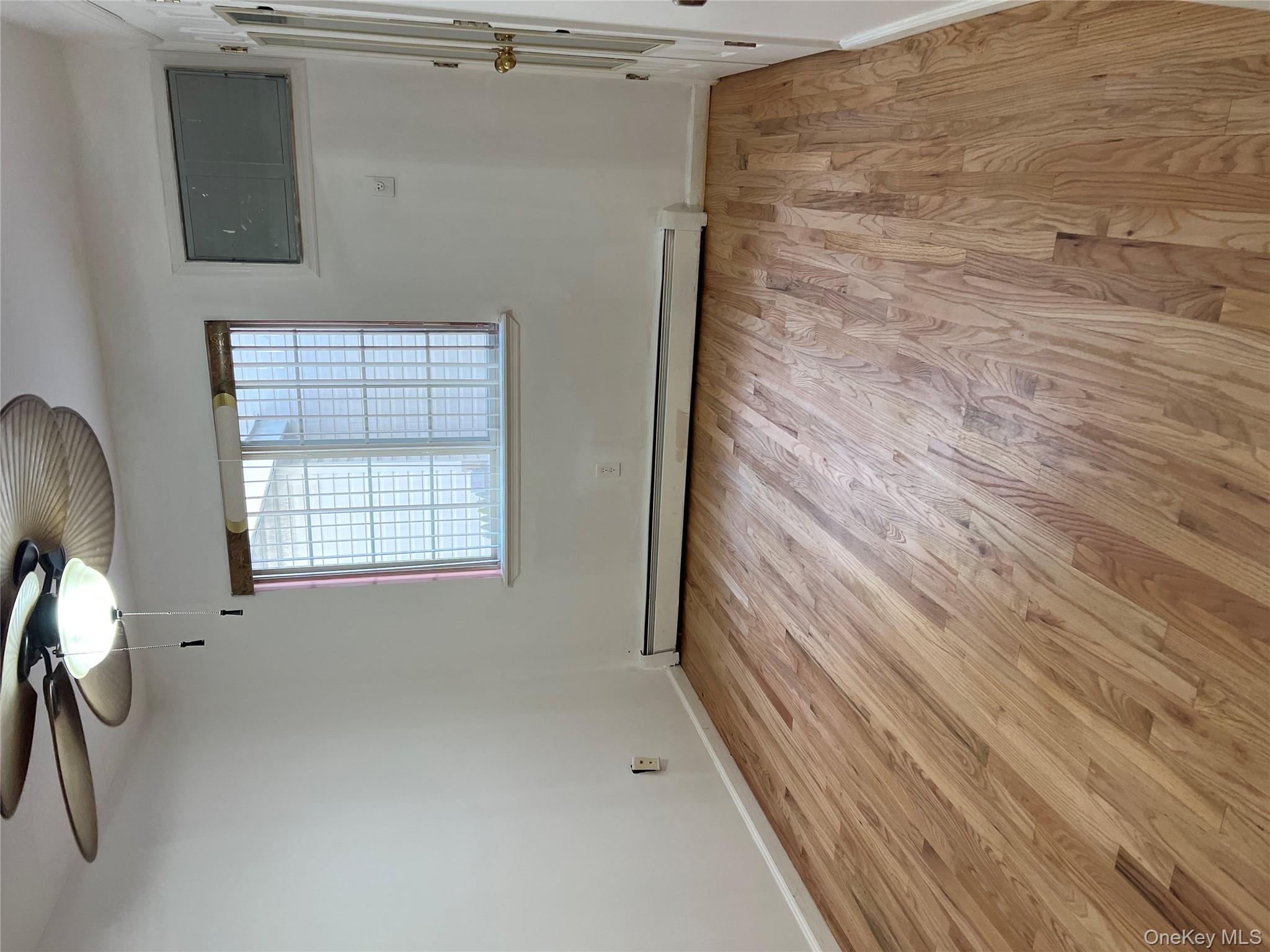 169-11 105th Avenue, Unit 1 Queens, NY 11433 - Photo 6 of 10 wooden floor in an empty room with a window