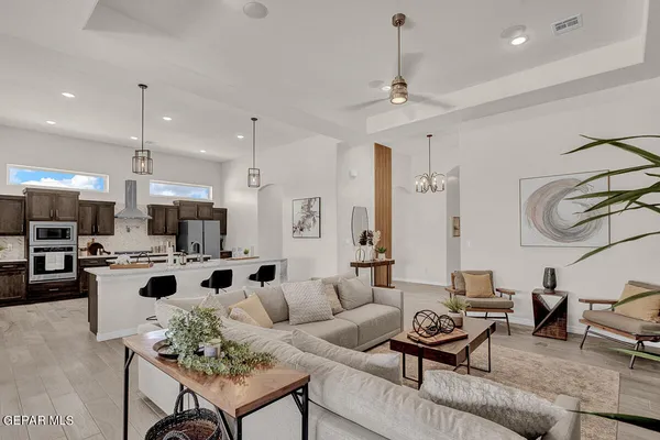 a living room with furniture kitchen view and a chandelier