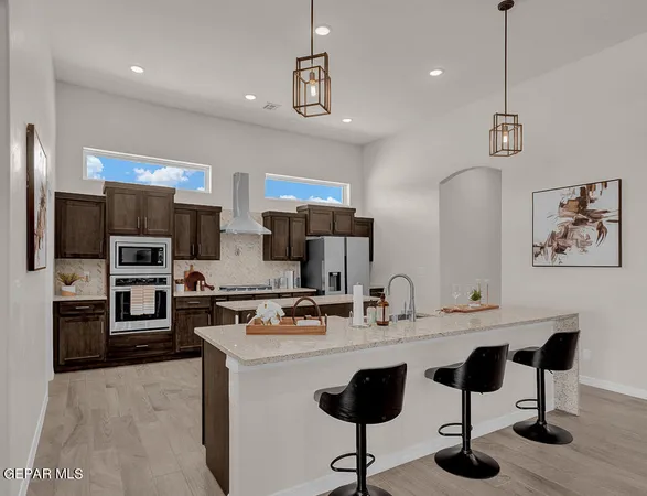 a kitchen with stainless steel appliances kitchen island granite countertop a sink a stove a refrigerator and chairs