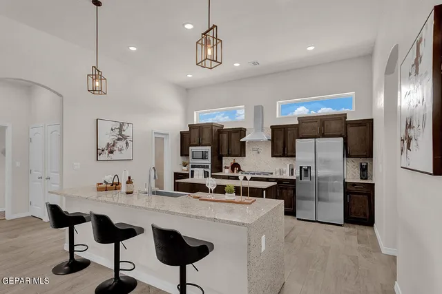 a kitchen with stainless steel appliances kitchen island granite countertop a refrigerator and microwave