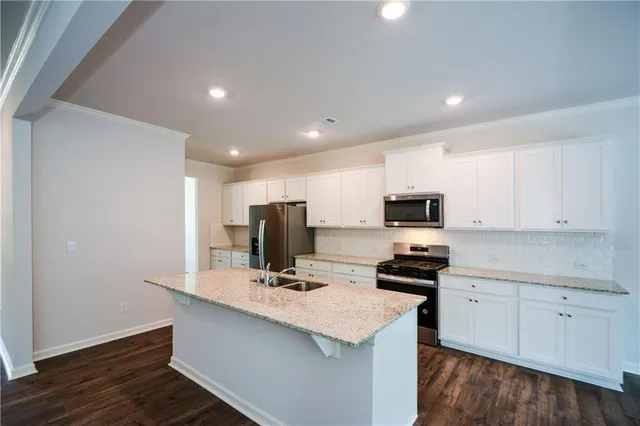 a kitchen with a sink a stove a refrigerator and white cabinets