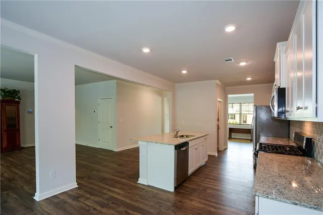 a large kitchen with stainless steel appliances granite countertop a large counter top a sink and a refrigerator