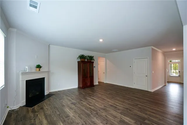 a view of an empty room with wooden floor and a fireplace