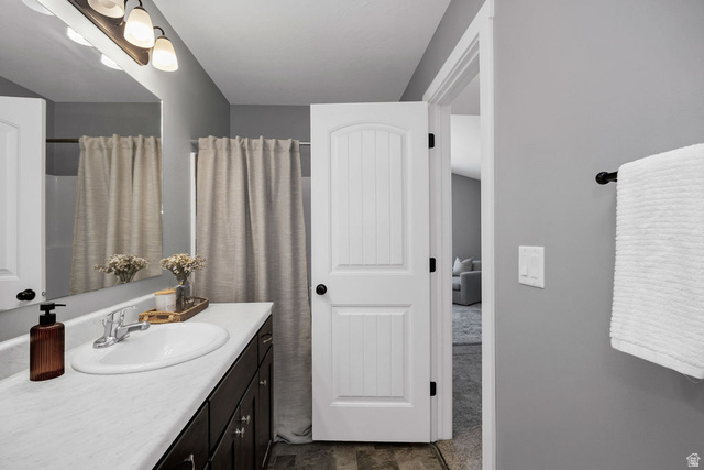 2483 South 1296th Street West Logan, UT 84321 - Photo 22 of 45 Full bathroom featuring a dark wood-finish vanity with a white countertop and integrated sink, chrome faucet, and overhead three-bulb vanity light fixture
