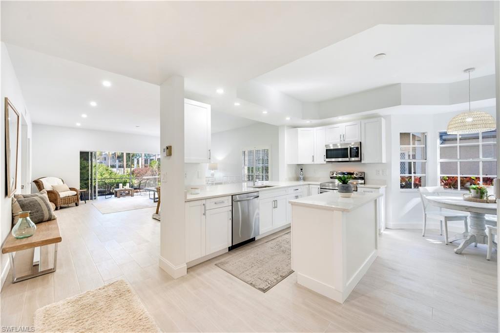2806 Aintree Lane, Unit H102 Naples, FL 34112 - Photo 25 of 26 Kitchen with open floor plan, white cabinets, a kitchen island, stainless steel appliances, and decorative light fixtures