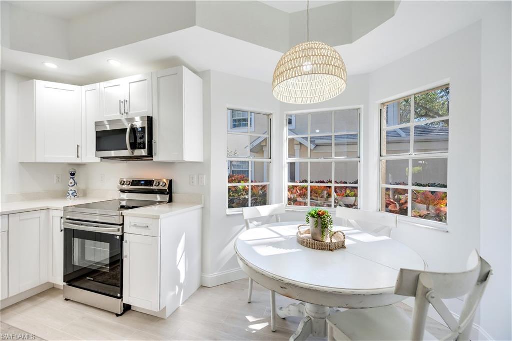 2806 Aintree Lane, Unit H102 Naples, FL 34112 - Photo 10 of 26 Kitchen with stainless steel appliances, light stone countertops, pendant lighting, white cabinetry, and a kitchen island