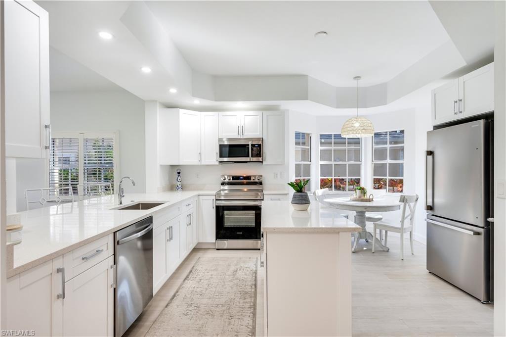 2806 Aintree Lane, Unit H102 Naples, FL 34112 - Photo 26 of 26 Kitchen featuring appliances with stainless steel finishes, white cabinetry, recessed lighting, light stone countertops, and open floor plan