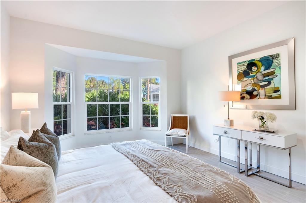 2806 Aintree Lane, Unit H102 Naples, FL 34112 - Photo 14 of 26 Bedroom featuring a closet, a ceiling fan, wood finish floors, and ensuite bath