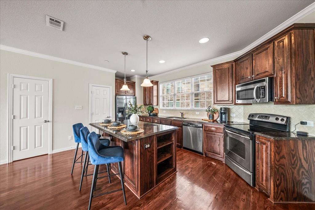 2700 Club Ridge Drive, Unit 34 Lewisville, TX 75067 - Photo 13 of 27 a kitchen with stainless steel appliances granite countertop a stove top oven a sink dishwasher a dining table and chairs with wooden floor