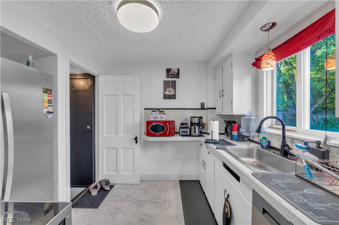 3962 Grosvenor Road South Euclid, OH 44118 - Photo 10 of 27 Bright kitchen space featuring a stainless steel sink with a matte black faucet, white cabinetry, and light-toned flooring