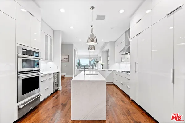 a kitchen with kitchen island a counter top space a sink stainless steel appliances and cabinets