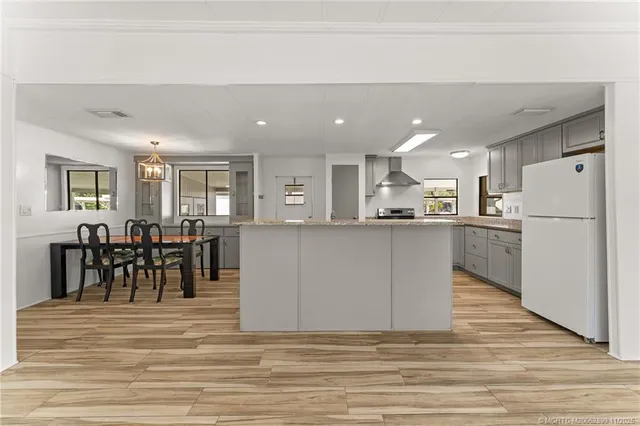 a view of kitchen with kitchen island a refrigerator cabinets a dining table and chairs