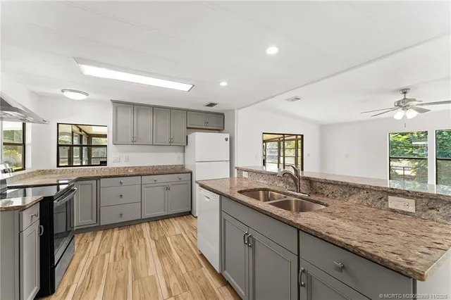 a kitchen with granite countertop stainless steel appliances a sink stove and cabinets