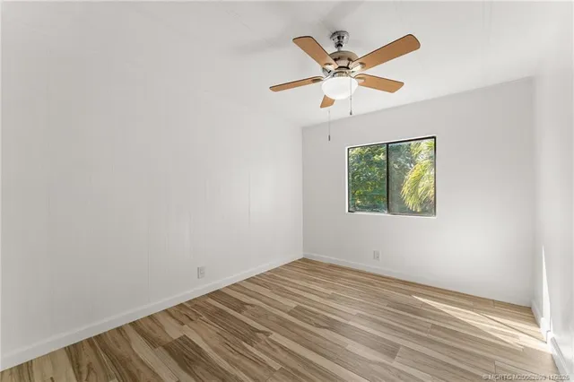 an empty room with window and ceiling fan