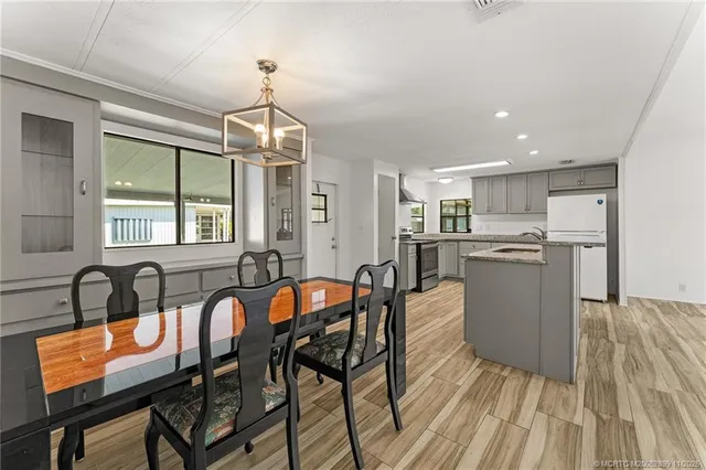 a kitchen with stainless steel appliances granite countertop a stove top oven a sink dishwasher a dining table and chairs with wooden floor