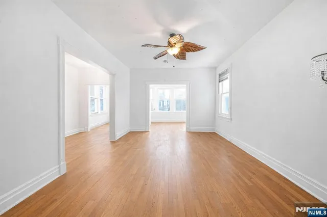 a view of an empty room with window and wooden floor