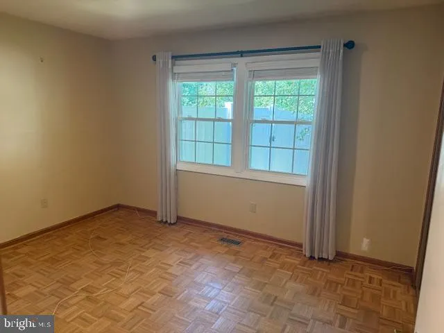 an empty room with wooden floor fireplace and windows