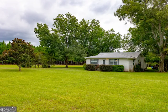 a white house with a big yard and large trees