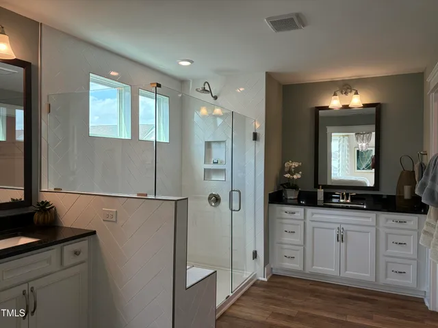 a bathroom with a double vanity sink mirror and shower
