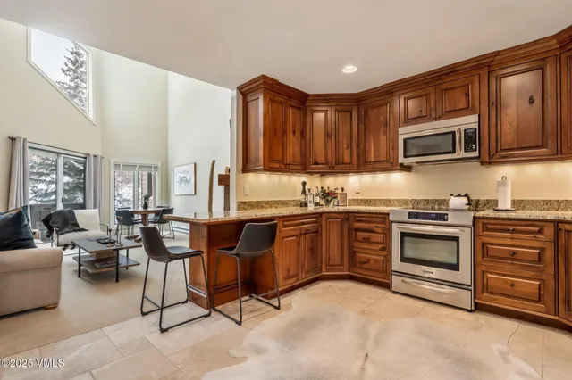 a kitchen with granite countertop a stove top oven a sink dishwasher a dining table and chairs with wooden floor