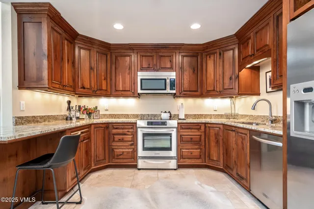 a kitchen with stainless steel appliances granite countertop wooden cabinets a sink and a stove