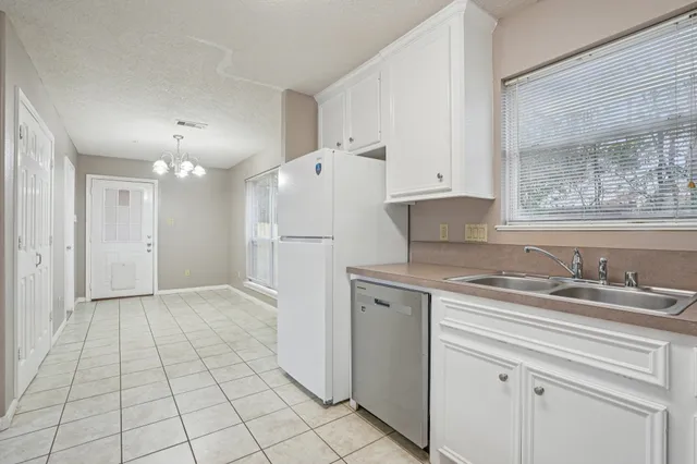 a kitchen with a sink a refrigerator a window and cabinets