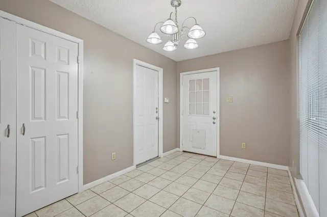 an empty room that has a chandelier fan and a bathroom